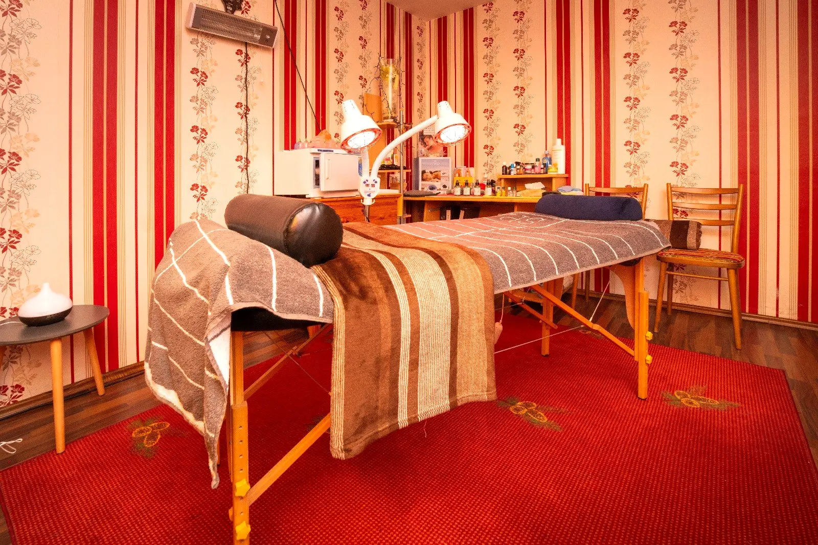 Behandlungsraum mit Massageliege, Handtüchern und warmem Licht